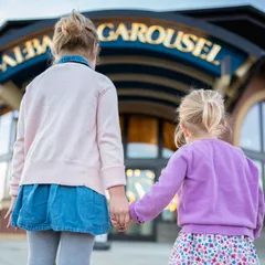 Two children prepare to ride the carousel in Albany, OR